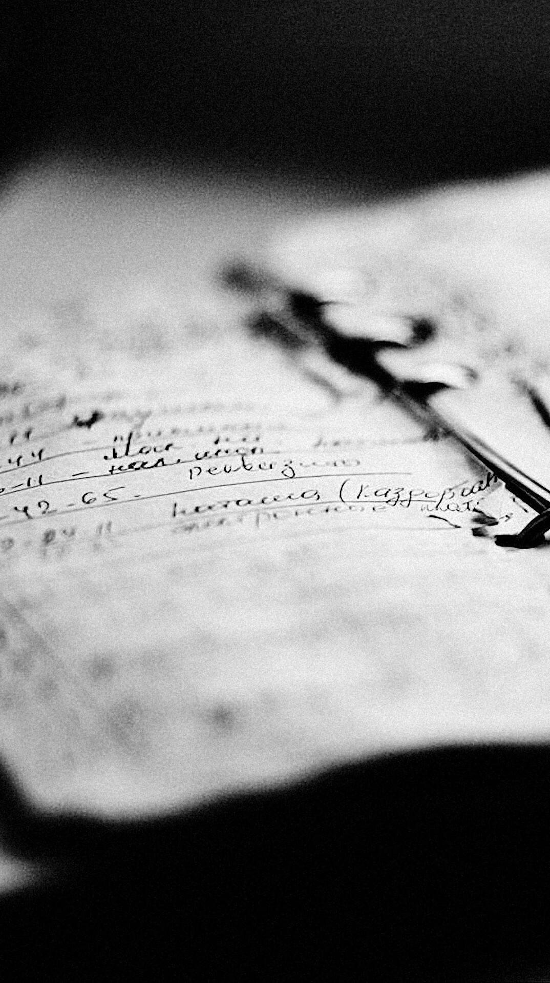 Close-up of an open notebook with handwriting and a pen